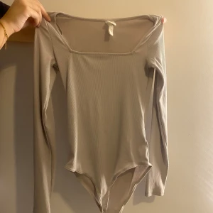Beige body - Stretchig ribbad body med kvadratisk form vid bysten. Sitter mycket fint och formar kroppen precis som den ska. Storlek Xs passar dock S också. 