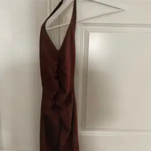 En glittrig brun klänning med halterneck, aldrig använd. 