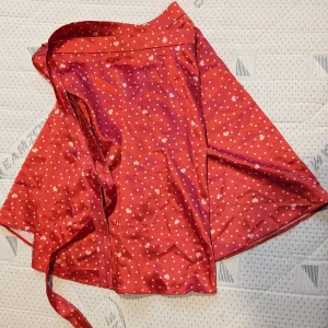 Omlottkjol - Snygg omlottkjol i satin från Asos. Tack vare att den knyts så är den väldigt justerbar och passar flera storlekar.  Köpare står för frakten.