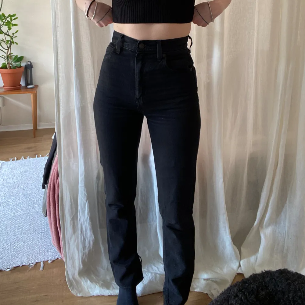 Svarta Levis jeans i modellen 70s High Slim Straight. Storleken är Waist 23 Lenght 31. Urtvättade svarta med uppklipps slits på insida ben/fot. Längden på byxbenet mätt från skrevet: 79-80 cm. Jeans & Byxor.