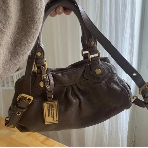 Marc Jacobs väska - Säljer min Marc Jacobs väska som är i nyskick💗 den är knappt använd och är supersnygg till allt!! Den är i en mörkare beige/grå nästan ljusbrun färg