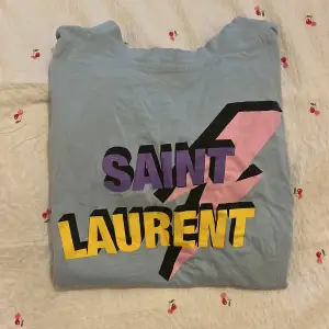 T-shirt med ”saint Laurent” tryck på. Storlek S. Nyskick - använt. Inga defekter eller lösa trådar. Använd gärna ”köp nu” funktionen 😊