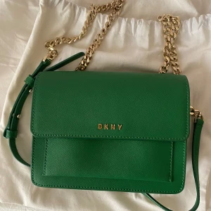 DKNY väska i helt nytt skick! - Ursnygg DKNY väska i grönt läder i helt nytt skick som dessvärre inte används längre. Kommer med orginal dust bag. Kan mötas upp i Lund. Kan postas men köpare står för frakt. Köpt är köpt gäller.💗💗