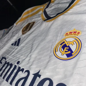 Vini Jr tröja - En mycket fin Real Madrid, Vini Jr tröja! Tröjan är helt ny och oanvänd! Top kvalitet! Tröjan är player version, har Club World Cup patch på brösten och UCL patch ärmen. Storlek S. Hör av er vid frågor :)