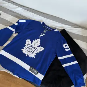 Säljer min Maple Leafs jersey med Tavares på ryggen. Den är i storlek L, som ni ser på sista bilden så är det ett litet hål på ryggen så även går igenom på framsidan. Annars är tröjan som ny. 