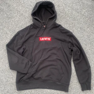 Svart hoodie - Säljer en svart hoodie från Levis🤩Deras märke på framsidan är broderat, & har en lapp med deras märke på baksidan🙌🏻I bra använt skick, har två fläckar på framsidan (se bild 5), vet ej vad det är men går nog bort i tvätten🤗I modellen ”Relaxed”, strl. M