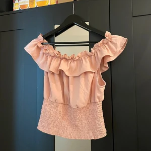 Rosa blus med volanger - Jag säljer en topp med massa fina detaljer och som har en ljus rosa nyans. Den har bara provats och är i strl L