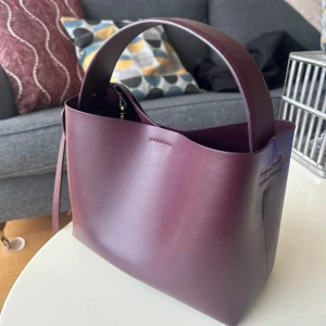 Väska arket - Säljer denna väska från Arket i skinn, i färgen Burgundy. Använt mycket sparsamt och har inga skador eller repor.   Nypris 