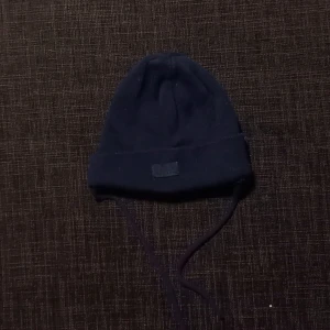 Marinblå vintermössa strl. 44 - Marinblå vintermössa till bebis i storlek 44. Snörning under halsen. I fint begagnat skick, inga hål eller fläckar.  Tvättad i parfymfritt tvättmedel och utan sköljmedel.