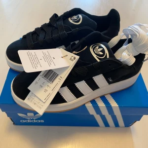 Nya Adidas Campus 00 - Adidas originals Campus 00s j Storlek: 36 2/3 Färg:CBLACK/FTWWHT/FTWWHT (svarta med vita ränder)  Ingår både svarta och vita skosnören.   Nya och oanvända. Ligger kvar i kartong. Sista paret!
