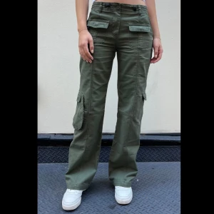 Kim cargo pants  - Lågmidjade gröna cargo pants från brandy melville ! Köpta för ett tag sedan men knappt använda. Justerbar midja. Bilderna är från brandy melville hemsidan ! Nypriset ligger på ungefär 500kr. Läs bio innan köp ! 😋