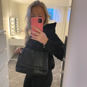 Svart handväska - Perfekt svart handväska från HM med en kedja som axelband. Bandet är justerbart så man kan antigen ha väskan som på bilden på axeln eller som crossbody bag! Den är något sliten men ändå bra skick!