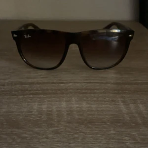 Ray-Ban svarta Wayfarer solglasögon - Säljer ett par klassiska Ray-Ban Wayfarer solglasögon i svart plast med mörka, tonade glas. Snygg och tidlös design med Ray-Ban-logga på skalmen. Perfekt accessoar för att lyfta din stil. Knappt använda, säljer på grund av att jag tröttnat på dem.