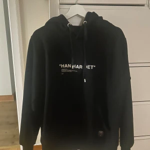 Svart hoodie med tryck HAN HAR DET - Svart hoodie med vit text 'HAN HAR DET' på bröstet och snörning i huvan. Gamla trycket så går inte att få tag på längre! Nypris 799.