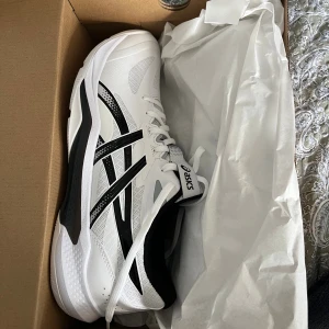 Asics Gel-Tactic 13 vit/svart strl 45 - Säljer ett par Asics Gel-Tactic 13 i vitt och svart. Helt nya, fortfarande i boxen. Säljer då jag inte behöver längre. Perfekta inomhusskor.