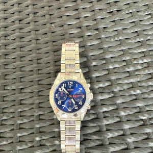 Festina barnklocka med blå urtavla - Snygg herrklocka från Festina med robust länkarmband i silverfärgat metall. Urtavlan är blå med vita siffror och detaljer i rött och silver. Klockan har tre mindre urtavlor och tydliga knappar på sidan. Perfekt accessoar för dig som gillar stilrena detaljer. Använd 1 gång original pris ;1450kr, pris kan diskuteras. Klockan kommer också i orginal förpackning.