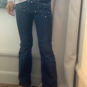 Mörkblå jeans med pärlor från Guess - Snygga mörkblå jeans från Guess med bootcut-modell. Jeansen har pärldetaljer och små hjärtan framtill som ger extra edge.💕