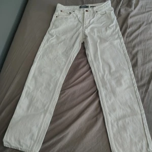 Vita jeansbyxor från Dressmann 29/30 - Snygga vita jeansbyxor från Dressmann i relaxed fit. Har bara använt de 2 gånger och det är en klassisk femficksmodell med raka ben och kopparfärgade nitar. Perfekta för dig som gillar en clean och enkel stil. 