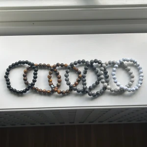 Set med pärlarmband i olika färger - Säljer ett set med sju elastiska pärlarmband i olika färger och stenmönster. Armbanden har runda pärlor i svart, brunt, grått, vitt och marmorerat mönster. Perfekt för att mixa och matcha till din stil. Snygga att bära både enskilt och tillsammans.