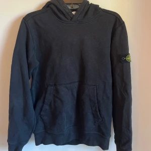 Svart Stone Island hoodie - Säljer denna snygga Stone Island hoodien som är i junior size men passar som XS/S, den är i mycket bra skick, nypris runt 3500 kr, mitt = 699 kr, pris kan diskuteras, skriv om minsta lilla fundering! 