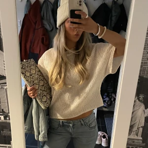Blus - Säljer en vit croppad blus med korta, vida ärmar och snyggt strukturerat tyg. Blusen har en lätt rynkad halsringning och är tillverkad i ett luftigt material som ger en avslappnad vibe. Perfekt att styla med jeans för en trendig look. Sänker inte priset!! Strl m men passar xs-m