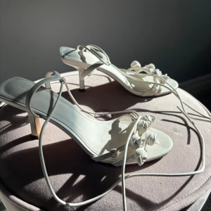 Vita klackskor - Använda en gång vid bal. Någon utav blommorna har gått av annars fint skick. Är storlek 36.