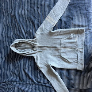 Grå hoodie från Stronger med dragkedja - Säljer en ljusgrå hoodie från Stronger i storlek S. Tröjan har hel dragkedja, huva med snörning och två stora fickor framtill. 🩷Säljer då den inte kommer till användning.