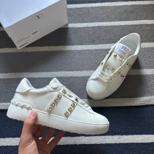 Valentino Opens/Rockstud - Vit/Guld - Tjena! Säljer nu dessa riktigt feta valentino skorna. Skicket på dessa är 10/10, och inga skador osv. Medföljer box, dustbag, påse osv. Storlek 38-39. Vid frågor kontakta gärna. Mer info finns på TikTok : AdamCloset Mvh Adam
