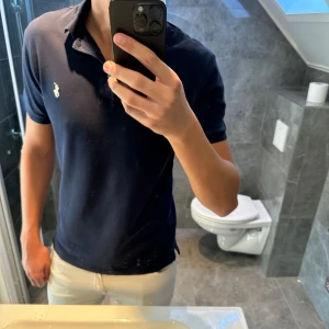 Mörkblå Polo Ralph Lauren piké - Riktigt schysst mörkblå Ralph lauren piké. Pikén är i bra skick och har inga defekter. Jag är 188cm lång och bär storlek M. Skriv vid frågor;) 