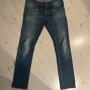 Nudie Jeans Grim Tim 32/32 blå jeans - Säljer ett par Nudie Jeans Grim Tim i klassisk blå tvätt med orange sömmar. Jeansen har rak passform. Pris kan diskuteras 