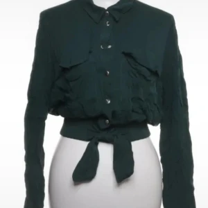 Mörkgrön skjorta med knyt från Tally Weijl - Mörkgrön skjorta från Tally Weijl med långa ärmar, knappar framtill och cool knytning i midjan. Skjortan har två bröstfickor och är tillverkad i ett lätt, skrynkligt tyg av 100% viskos. Perfekt för dig som gillar en trendig och avslappnad look.