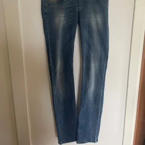 Blå jeans från Killah Rag Flake - Snygga blå jeans från Killah Rag Flake med klassisk femficksdesign och raka ben. Jeansen har en cool tvätt med ljusare partier och detaljerade bakfickor. Perfekta för dig som gillar en avslappnad men stilren look.tveka inte på att höra av er om ni har frågor 🥰