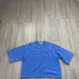 Blå stickad tröja från Pigalle - Blå stickad tröja från Pigalle  med kortare ärmar. Tröjan har rund halsringning och är gjord i ett mjukt material som känns skönt mot huden. Perfekt för dig som gillar stockholm stil