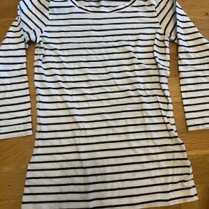 Randig långärmad tröja från Sisters - Långärmad tröja från Sisters i vitt med svarta horisontella ränder. Tröjan har en klassisk rund halsringning och är tillverkad i mjuk bomull.