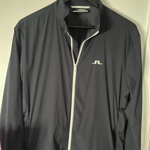 J.Lindeberg vindjacka - Säljer denna stilrena vind/regnjacka från J.lindeberg då den är lite stor för mig. Storlek M. Mycket bra skick. Ny pris: 1500, mitt pris 450kr.