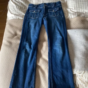 Blå bootcut jeans från Gina Tricot - Snygga blå jeans från Gina Tricot i bootcut-modell med markerade sömmar och coola fickdetaljer fram. Klassisk femficksdesign och normal passform. Perfekta för dig som gillar en tidlös jeanslook med lite extra attityd.