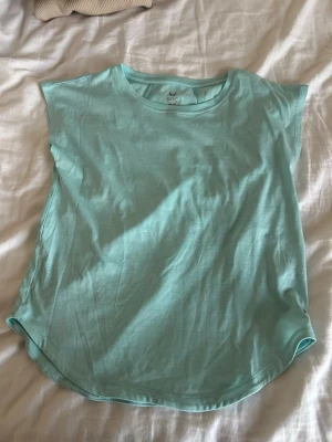 Ljusblå träningstopp från SOC - Säljer en ljusblå träningstopp från SOC i ett mjukt och lätt syntetmaterial. Toppen har rund halsringning, ärmlös design och diskreta sömmar som ger en sportig look. Perfekt för dig som vill ha en enkel och bekväm topp till träningen.