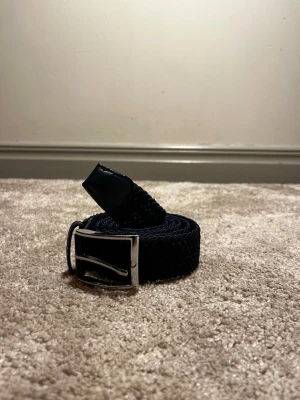 Flätat bälte från Ragazzo  - Ett stilrent flätat bälte från Ragazzo i färgen marinblå. Aldrig använt!  125cm. Hör av er vid frågor eller funderingar! 