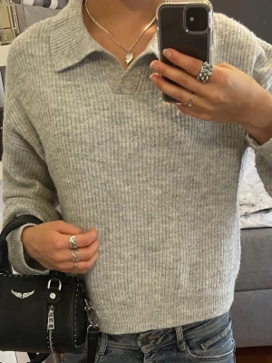 Ljusgrå stickad pikétröja - Grå stickad tröja från Kappahl med krage, ribbad struktur och långa ärmar. Passar XS/S.