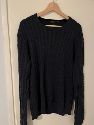 Mörkblå stickad tröja Tiger of Sweden - Snygg mörkblå stickad tröja från Tiger of Sweden, tillverkad av fin italiensk garn. Står storlek L men passar både M & L.