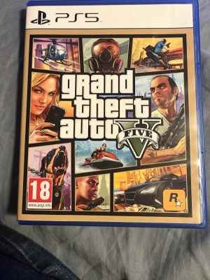 Grand Theft Auto V (GTA V) PS5 - Grand Theft Auto V till PlayStation 5 erbjuder förbättrad grafik, snabbare laddningstider och 60 FPS gameplay. Upplev en öppen värld fylld av action, äventyr och online-möjligheter. Omslaget och fodralet är i mycket gott skick.