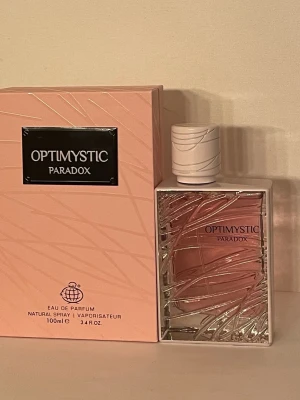 Optimystic Paradox fragrance world - Optimystic Paradox fragrance world  är en Eau de Parfum på 100 ml, Toppnoter: mandarin, bergamott, päron. Mellannoter: apelsinblom, neroli, jasmin sambac. Basnoter: bourbonvanilj, vit musk, bensoin. Påminner om Prada paradoxe. En mjuk feminin doft som många gillar. 