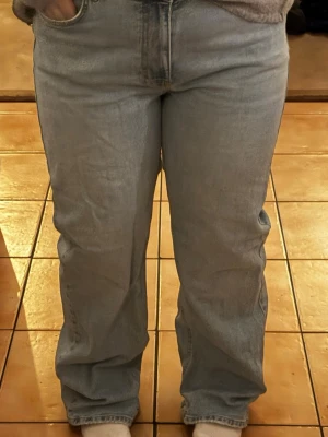 Ljusblå raka jeans - Säljer ett par ljusblå jeans med klassisk femficksdesign och rak passform. Jeansen har normal midja och är tillverkade i mjukt denimtyg. Perfekta för dig som gillar en chill och enkel stil. Passar till sneakers eller boots.