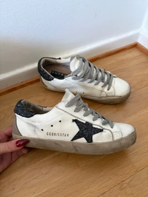 Golden Goose superstar - Golden Goose superstars, vita med svart glittrig stjärna. Skorna är andvända i bra skick men inga defekter. Storlek 37 eu