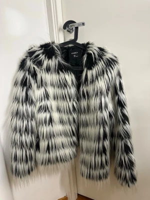 Svartvit pälsjacka från Lindex, S - Säljer en fluffig och cool svartvit pälsjacka från Lindex i storlek S. Jackan har ett randigt mönster med långa, mjuka pälsstrån och är helfodrad med svart insida. Perfekt för dig som vill sticka ut och hålla dig varm under höst och vinter. Köpt för 1100kr säljer för 300kr, pris kan diskuteras 💕
