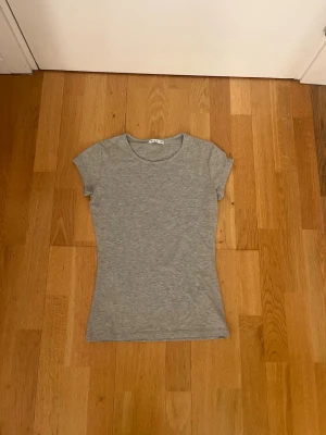 Ljusgrå t-shirt från Vila XS - En basic ljusgrå t-shirt från Vila i storlek XS. T-shirten har rund halsringning. Perfekt att matcha med jeans eller kjol.