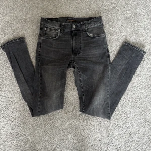 Svart skinny jeans från Nudie Jeans - Snygga svarta jeans från Nudie Jeans i modellen skinny fit. Jeansen har klassisk femficksdesign, svarta broderade detaljer på bakfickorna. 