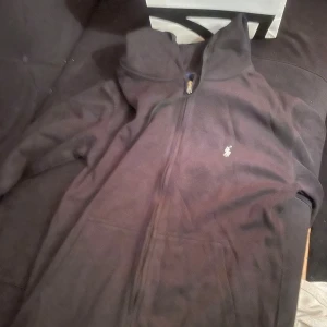 Svart hoodie från Polo Ralph Lauren - Svart hoodie från Polo Ralph Lauren med dragkedja framtill och klassisk vit broderad logga på bröstet. Pris kan diskuteras i dm