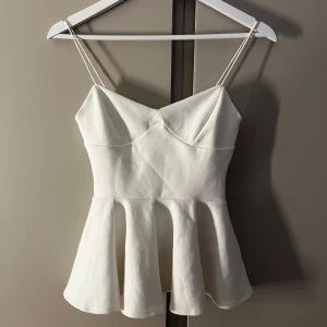 Vit peplum linnetopp med smala axelband från Zara - Säljer min fina vita topp från Zara. Den är i storlek S och andvänd högst 5 gånger i somras.