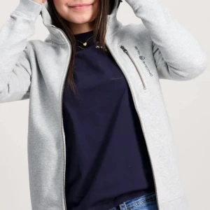 Ljusgrå hoodie från Sail Racing - Ljusgrå hoodie från Sail Racing med dragkedja framtill och en extra bröstficka med zip. Perfekt för chill dagar och snygg till jeans. Diskret logga på bröstet och bak på huvan. Mjuk bomullsblandning. Säljer på grud av att jag inte hwr någon användning för den. Tröjan har en liten fläck och ett liten hål fickan, 170 i barnstorlek men passar mig som har XS/S